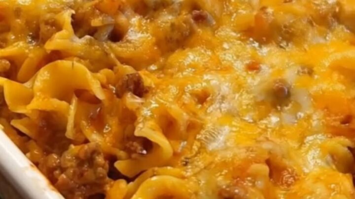 A hearty cheesy beef noodle casserole in a white baking dish, fresh from the oven with bubbly melted cheese.