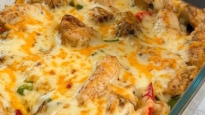 A golden, cheesy chicken fajita rice casserole in a glass baking dish with a dramatic cheese pull.