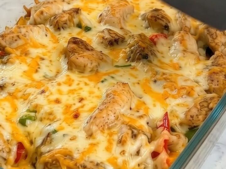 A golden, cheesy chicken fajita rice casserole in a glass baking dish with a dramatic cheese pull.