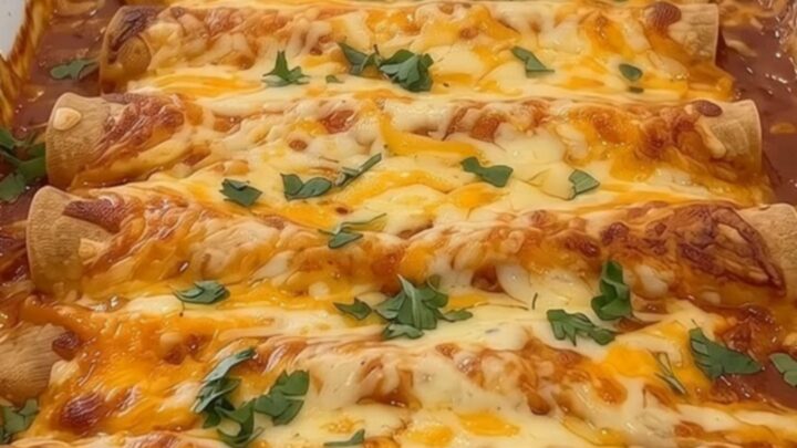 Cheesy ground beef enchiladas baked in a white ceramic dish topped with red sauce, cheese, and cilantro.