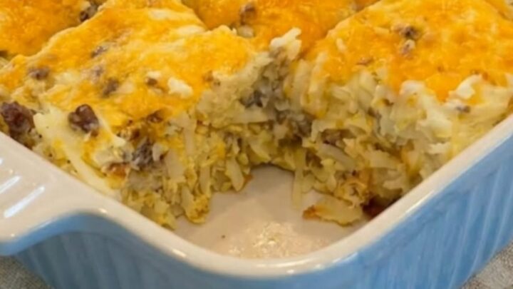 A golden-brown sausage and hash brown breakfast casserole in a blue ceramic dish.