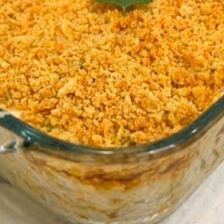 A warm, creamy chicken casserole in a glass dish with a golden, buttery cracker crust and fresh parsley.