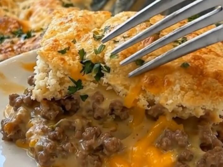 A golden, cheesy ground beef cobbler in a white baking dish, showing a steamy, hearty filling.