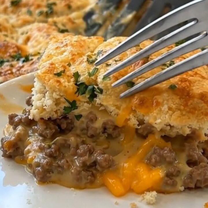A golden, cheesy ground beef cobbler in a white baking dish, showing a steamy, hearty filling.