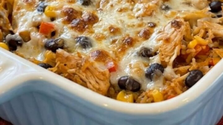 A cheesy chicken burrito casserole in a blue fluted baking dish, showing melted cheese and visible chicken and beans.