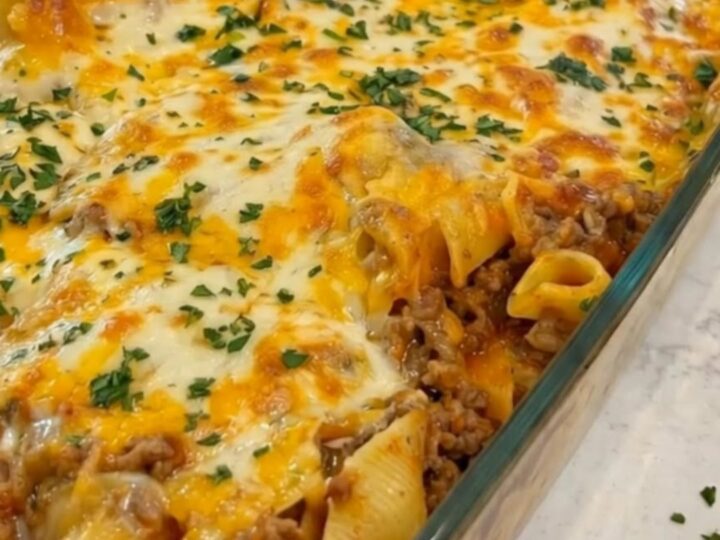 A steaming, cheesy beef and noodle casserole in a glass dish with a golden-brown melted cheese top.