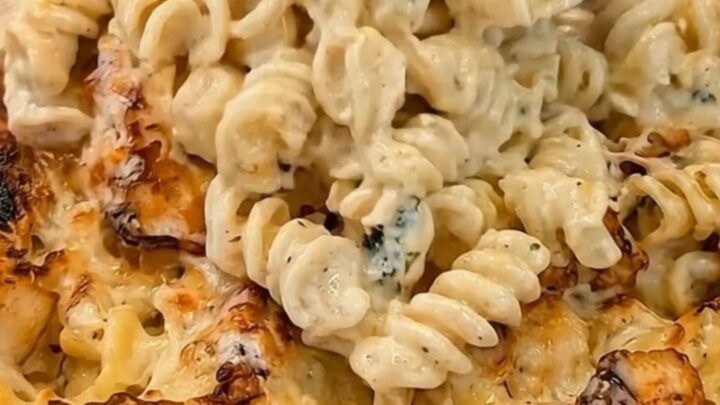 A golden-baked creamy chicken alfredo pasta casserole in a ceramic dish, showing bubbling sauce and steam.