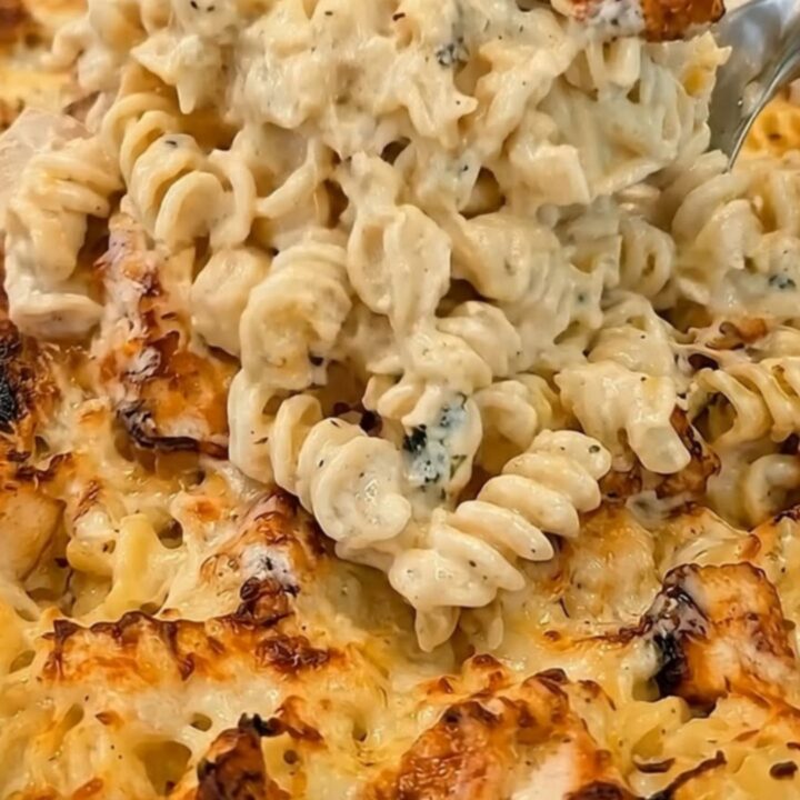 A golden-baked creamy chicken alfredo pasta casserole in a ceramic dish, showing bubbling sauce and steam.