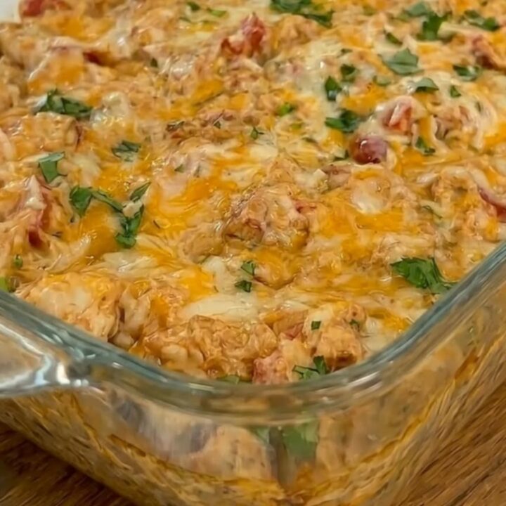 A golden, bubbling queso chicken and rice casserole in a glass baking dish, fresh from the oven.
