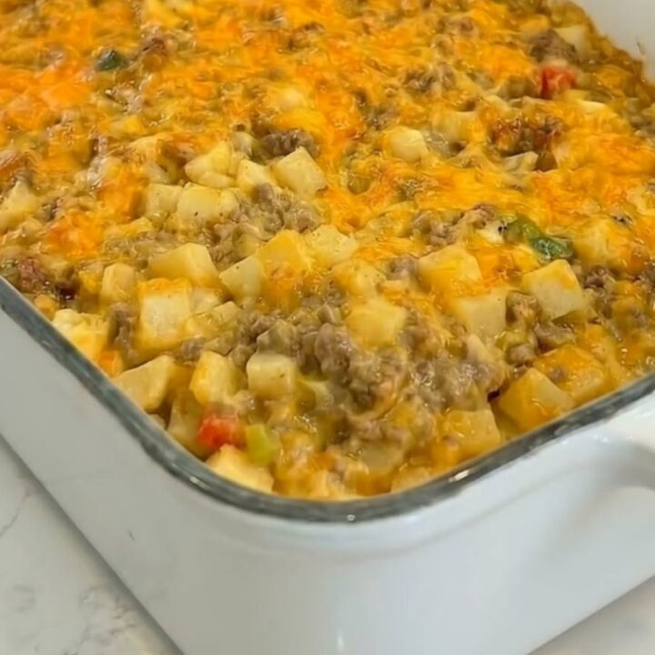 A golden, bubbly cheesy ground beef and potato casserole in a white baking dish.
