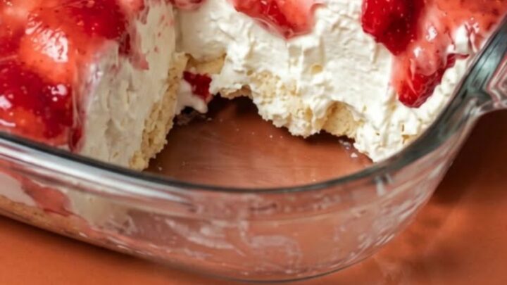 A clear glass dish filled with layers of angel food cake, creamy filling, and topped with fresh sliced strawberries.