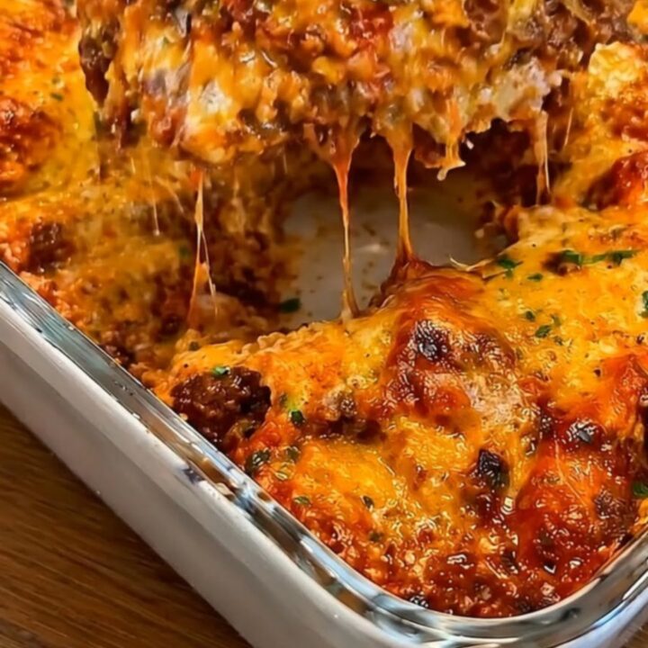 A steaming portion of smoked beef enchilada casserole being lifted from a baking dish with a spatula, showing a cheese pull.