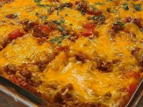 A golden, bubbling cheesy taco squares casserole in a glass dish with a spatula lifting a portion.