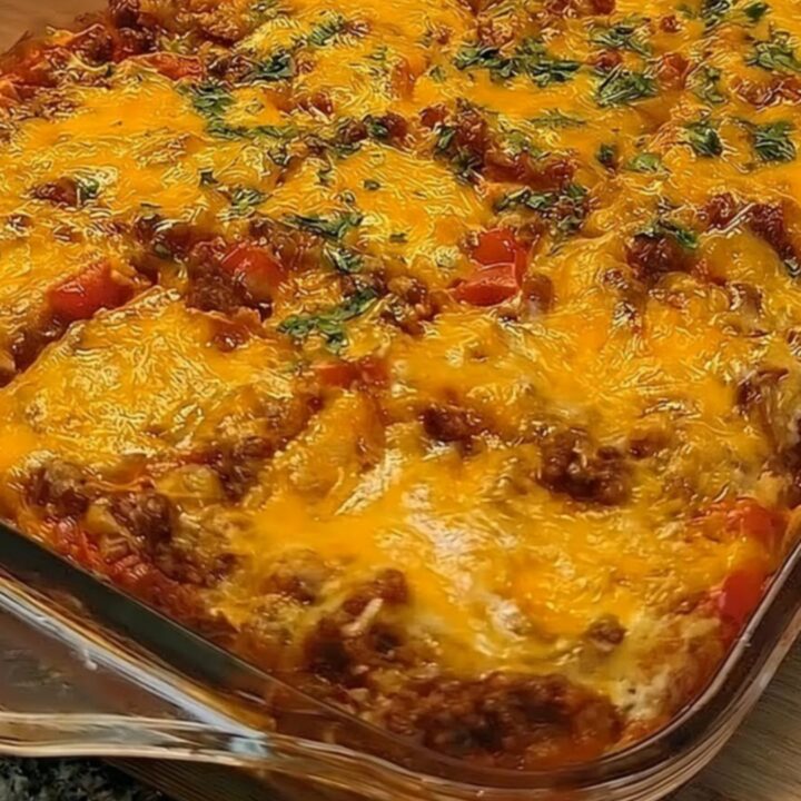 A golden, bubbling cheesy taco squares casserole in a glass dish with a spatula lifting a portion.