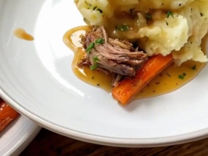 A close-up of a hearty portion of herb butter chicken with roasted carrots and creamy mashed potatoes.