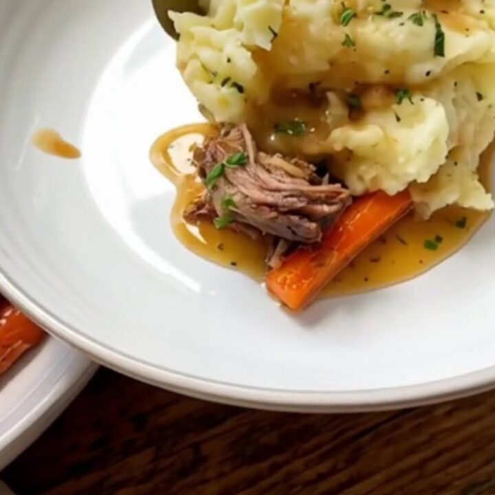 A close-up of a hearty portion of herb butter chicken with roasted carrots and creamy mashed potatoes.