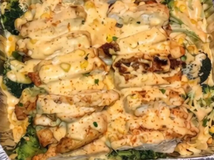 A steaming, creamy chicken and broccoli casserole in a foil baking dish, showing melted cheese and tender pieces of chicken.