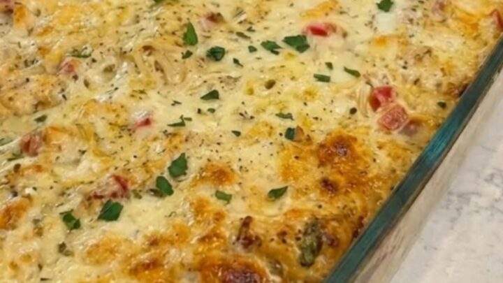 A steaming, creamy Texas chicken spaghetti bake in a glass dish with a long cheese pull.