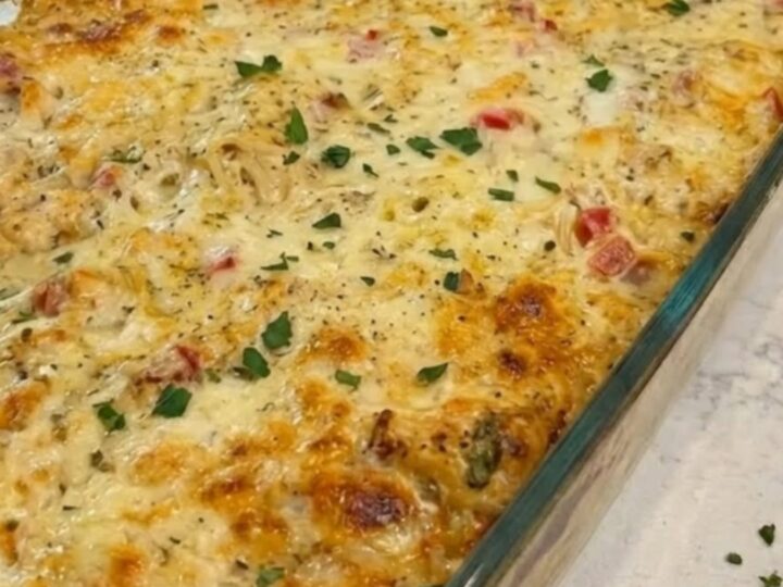 A steaming, creamy Texas chicken spaghetti bake in a glass dish with a long cheese pull.