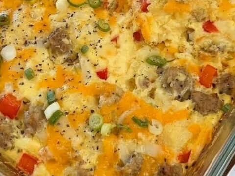 A warm, cheesy breakfast egg casserole in a glass dish with a slice being lifted out.