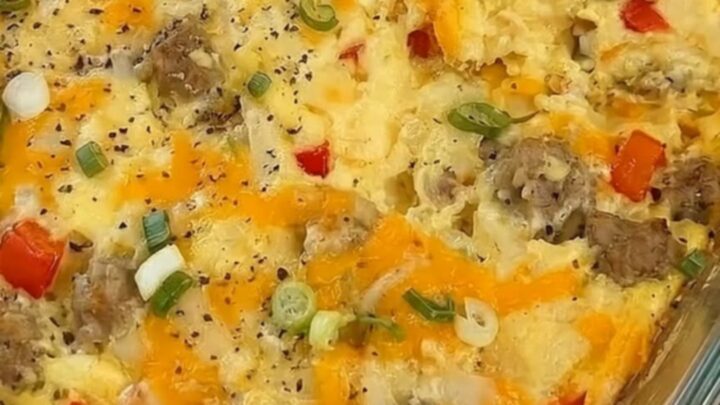 A warm, cheesy breakfast egg casserole in a glass dish with a slice being lifted out.