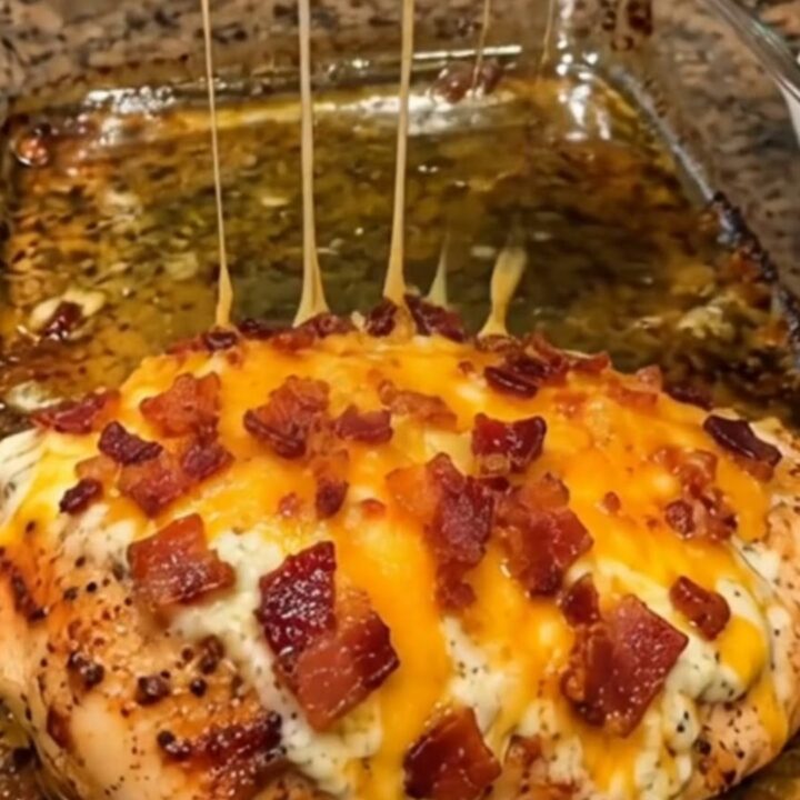 Loaded bacon cheddar chicken in a glass dish with melted cheese and crispy bacon.