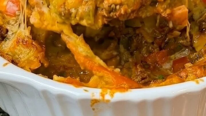 A bubbly, cheesy Mexican ground beef casserole in a fluted ceramic dish.
