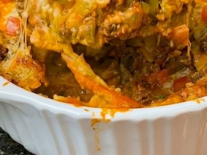 A bubbly, cheesy Mexican ground beef casserole in a fluted ceramic dish.