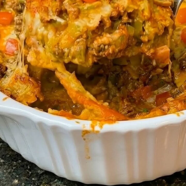 A bubbly, cheesy Mexican ground beef casserole in a fluted ceramic dish.
