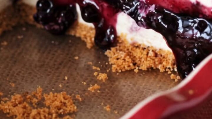 A slice of no-bake blueberry cheesecake pie on a white plate with a fork resting nearby.