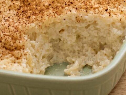 A ceramic dish filled with creamy baked rice pudding, dusted with cinnamon, ready to be served.
