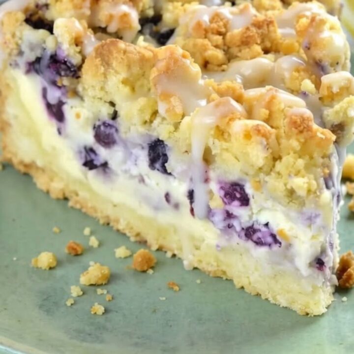A slice of blueberry cheesecake crumb cake on a plate showing the creamy center.
