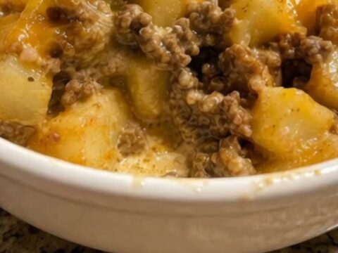 A steaming bowl of creamy beef and potato taco bowl topped with melted cheddar cheese.