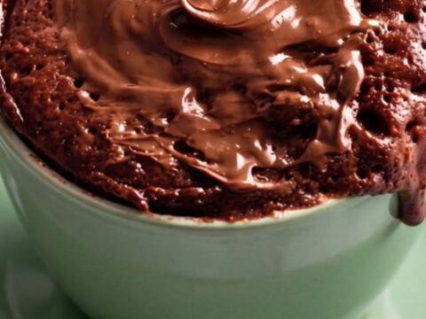 A warm, fudgy chocolate mug cake in a sage green mug with a glossy melted chocolate top.