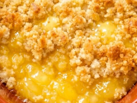 A close-up of a spoon scooping warm lemon dump cake from an orange ceramic dish