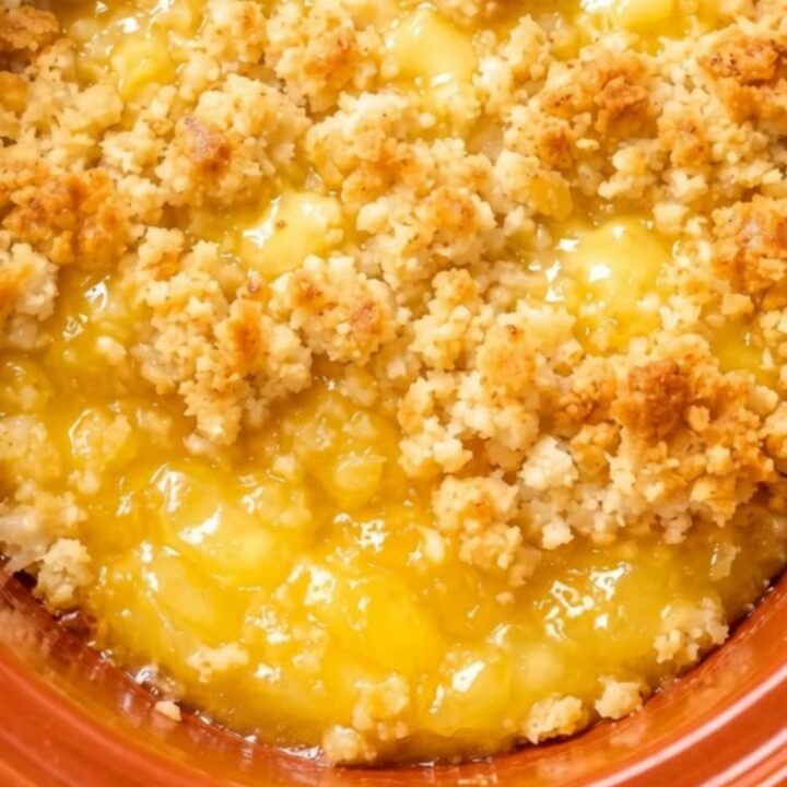 A close-up of a spoon scooping warm lemon dump cake from an orange ceramic dish