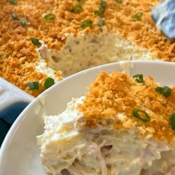 A golden, bubbly Million Dollar Chicken Casserole in a white ceramic dish with a crispy cracker topping.