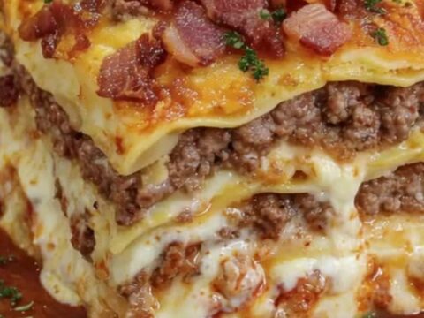 A close-up of a slice of parmesan garlic bacon cheeseburger lasagna showing melty cheese layers.