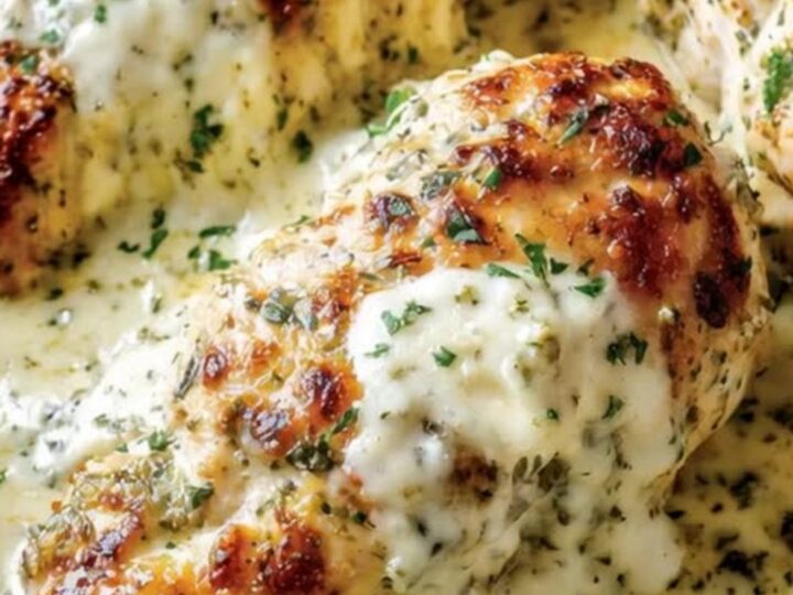 A golden baked chicken breast in a skillet covered in bubbly melted mozzarella and cream cheese.