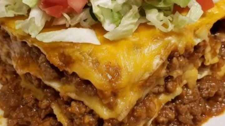 A steaming, cheesy taco lasagna casserole in a glass baking dish, ready to be served.