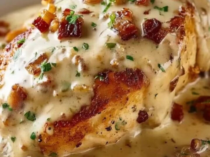 Golden-brown smothered chicken breast topped with crispy bacon and fresh parsley in a creamy sauce.