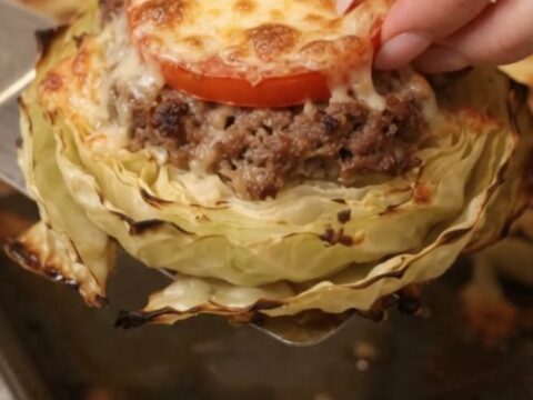 A close-up of a perfectly roasted cabbage round topped with browned ground beef and melted bubbly mozzarella cheese.