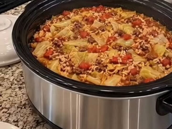 A steaming, hearty cabbage roll casserole served in a white bowl with a spoon.