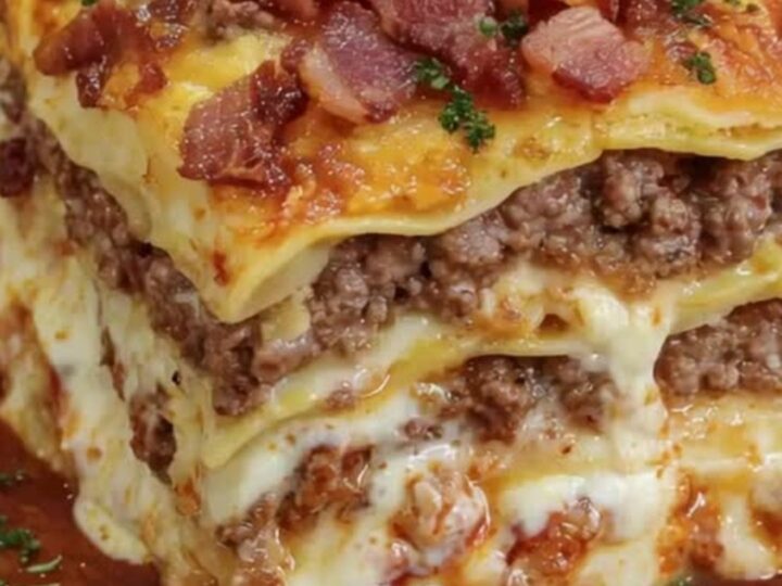 A slice of parmesan garlic bacon cheeseburger lasagna showing distinct layers and crispy bacon on top.