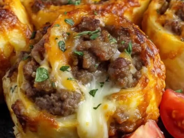 Golden brown garlic butter cheeseburger rollups resting on a dark plate with a fresh herb garnish.