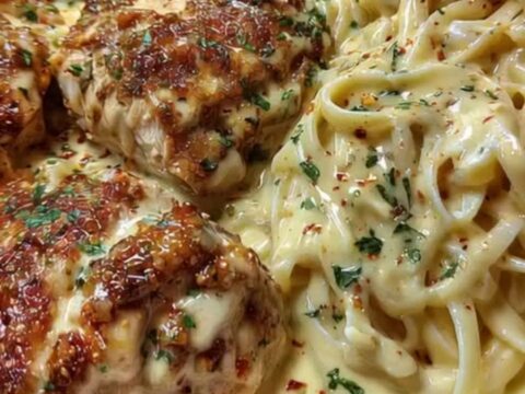 A close-up of creamy Cajun chicken Alfredo with golden-brown chicken slices on a white platter.