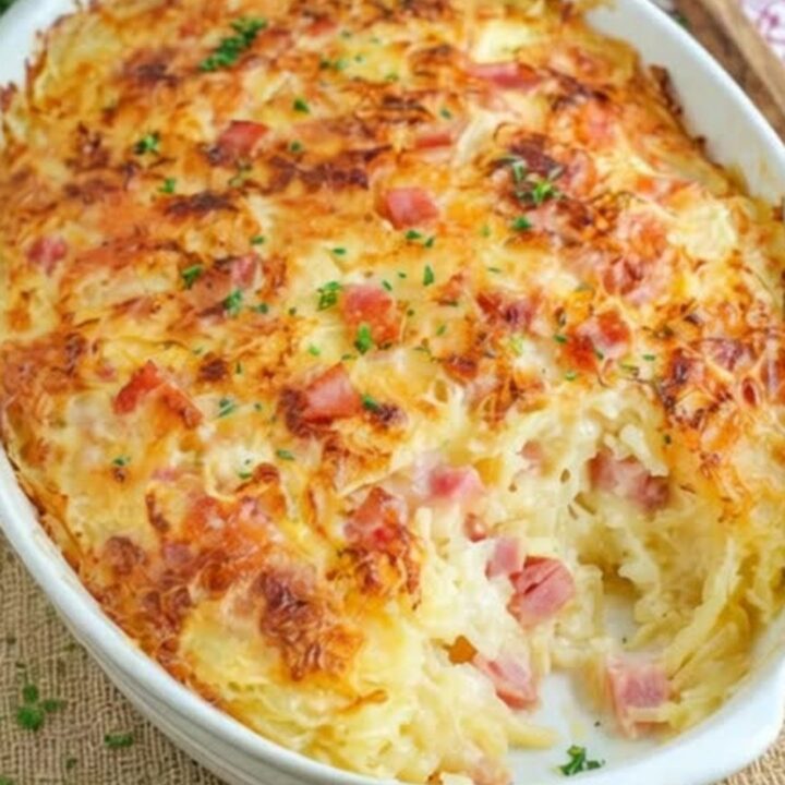 A golden-brown ham and cheese hash brown casserole in a white baking dish, fresh from the oven.