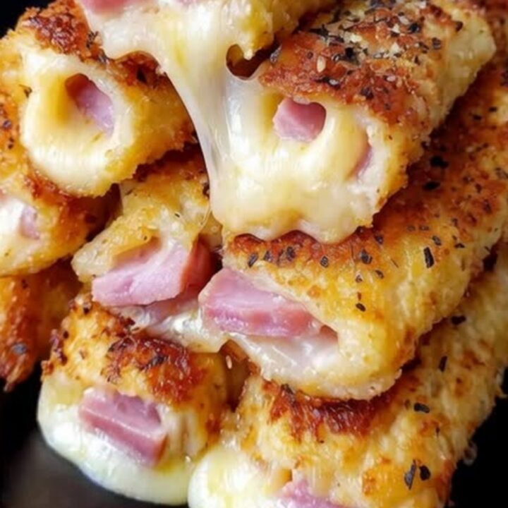 Golden-brown baked ham and mozzarella roll-ups stacked on a serving tray.