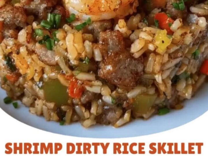 Steaming cast-iron skillet loaded with seared shrimp, browned sausage, and dirty rice.