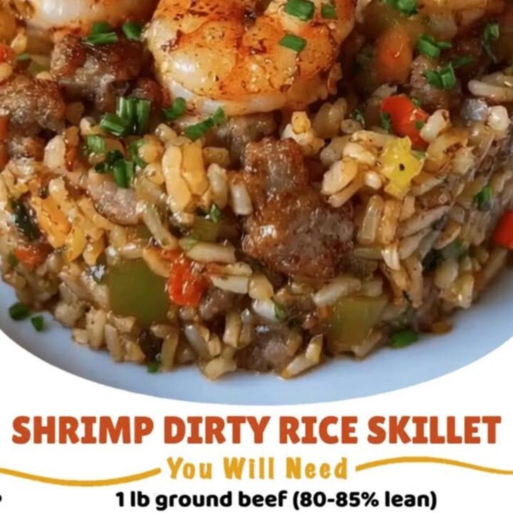 Steaming cast-iron skillet loaded with seared shrimp, browned sausage, and dirty rice.